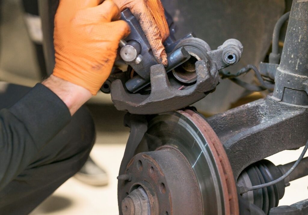 Close-up of worn brake pads and RV axle components during an on-site repair