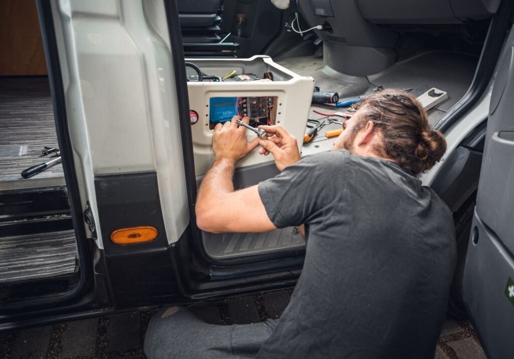 Certified RV electrician standing beside a service van parked at an RV park near Hoover, AL